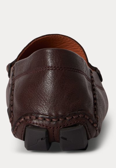 Καφέ σκούρο δερμάτινο παντόφλα, φαίνεται από πίσω, με ορατή ραφή και δύο λαστιχένιες λαβές στη φτέρνα της σόλας.