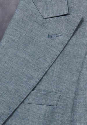 Ljusblå blazer med en texturerad tyg, knäppta slag och en enkel ficka; detaljerad sömnad framhäver designen.