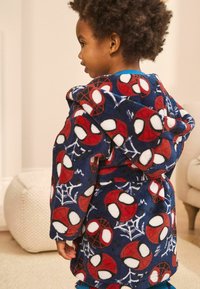 Navy fleece kylpyhuppu, jossa on yksityiskohtaisia Spider-Man -kuvioita punaisena, valkoisena ja sinisenä. Hupullinen ja vyötetty.