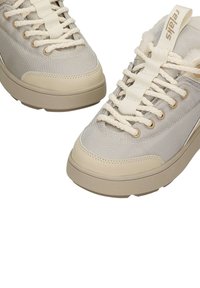Beżowe trampki z teksturowanym materiałowym wierzchem, wyposażone w kremowy system sznurowania, gumową podeszwę oraz subtelne logo na języku.