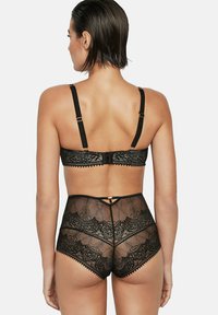Zwart kanten lingerieset met een beha met verstelbare bandjes en een haaksluiting, gecombineerd met tailleslip met bloemmotieven.