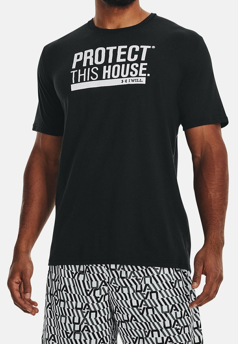 T-shirt noir à manches courtes en coton avec un col rond, portant la mention "PROTEGEZ CETTE MAISON." imprimée en blanc sur le devant en lettres capitales.