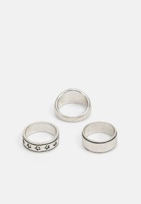 Tre sølv ringe med varierende design: en glat, en med stjernes mønster, og en med en sort linje accent. Alle har en poleret overflade.
