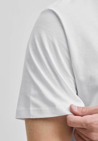 Weißes Baumwoll-T-Shirt mit Rundhalsausschnitt, kurzen Ärmeln und einer weichen Textur. Der Stoff fällt glatt und hat keine sichtbaren Muster.