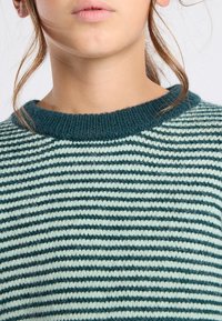Maglione a righe lavorato a maglia con colletto a coste di colore teal, caratterizzato da righe orizzontali alternate di verde chiaro e verde scuro.