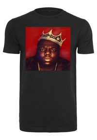 Juodas medvilninis t-shirt su ryškiu piešiniu, kuriame pavaizduotas vyras su auksine karūna, ant raudono fono. Apvalaus kaklo dizainas.