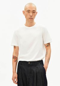 Wit katoenen t-shirt met een ronde hals en korte mouwen, gecombineerd met donkerblauwe denim broek met knopen en zijzakken.