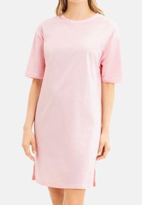 Rosa bomullsklänning med korta ärmar, rund halsringning, rak skärning och sidoflikar vid nederkanten, med en mjuk struktur.