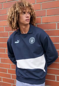 Sweatshirt cu guler polo, în nuanțe de bleumarin și alb, cu un logo și un design cu dungi orizontale contrastante, fabricat dintr-un material moale.
