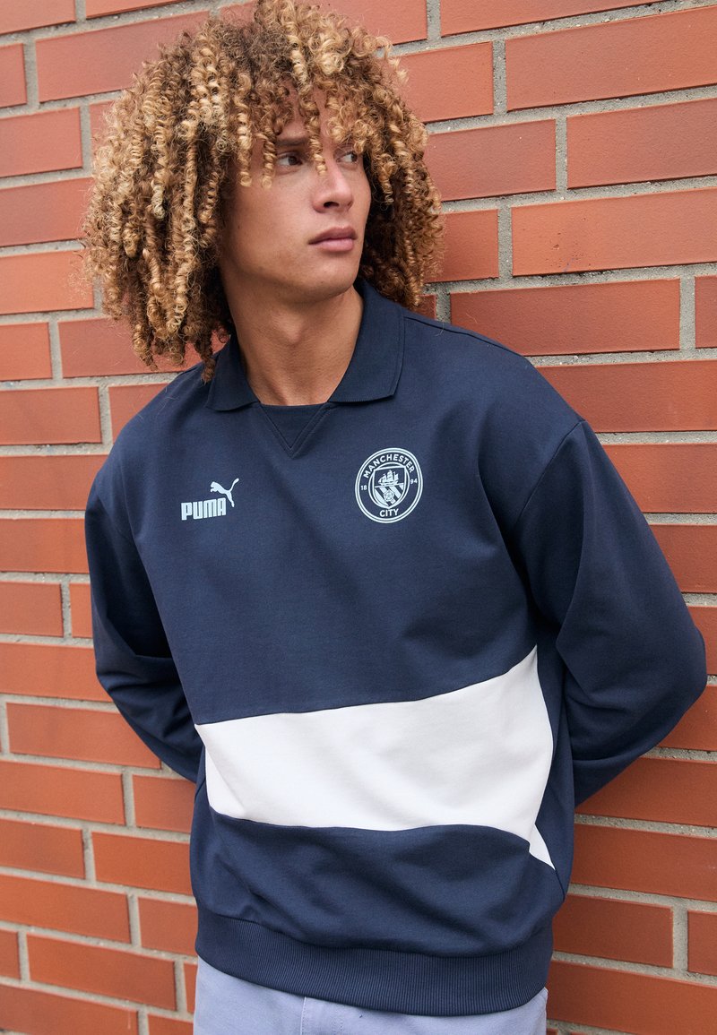 Sweatshirt cu guler polo, în nuanțe de bleumarin și alb, cu un logo și un design cu dungi orizontale contrastante, fabricat dintr-un material moale.