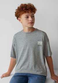 Grijze katoenen t-shirt met korte mouwen, voorzien van een witte tekstafbeelding "INNOVATIVE" op de borst. Casual fit, zachte textuur.