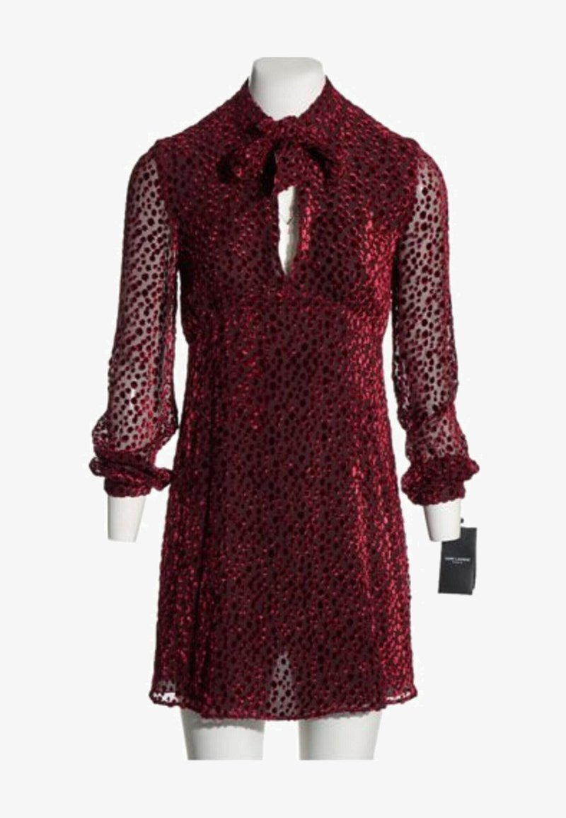 Robe en velours rouge avec manches longues transparentes, poignets volantés, nœud de cravate au cou et encolure en trou de serrure sur un mannequin blanc.