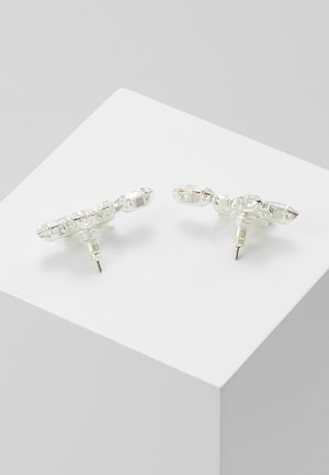 Paire de boucles d'oreilles clous transparentes avec des perles rectangulaires facettées disposées en motif géométrique sur une surface blanche.