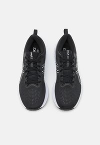 Black athletic shoes with a textured upper, white accents, and a lace-up design. Features a padded collar and lightweight sole.