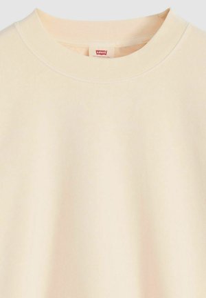 Sudadera beige claro con cuello redondo, confeccionada en material suave, con una pequeña etiqueta roja de Levi's en el interior del cuello. Textura lisa.