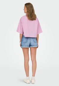 Lyserødstribet, cropped skjorte med korte ærmer, parret med lyseblå denimshorts. Båret med hvide sko og ankelstrømper.