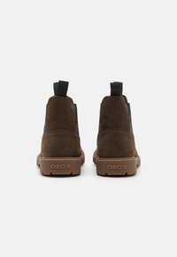 Stivaletti in suede marrone con pannelli laterali elasticizzati, due linguette per il sollevamento e una suola in gomma con marchio GEox sul tallone.