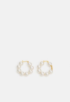 Boucles d'oreilles en forme de cercle ornées de perles, avec un fermoir en métal doré. Le design comprend plusieurs perles blanches lisses disposées en forme circulaire.