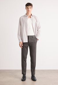 Striped button-up shirt with white and purple stripes, paired with gray trousers and black shoes. Sleek design, neutral colors, and modern fit.