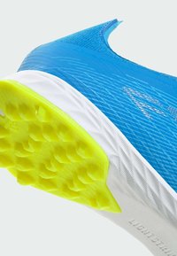 Gros plan sur une chaussure de sport bleue avec une semelle intermédiaire blanche et une semelle extérieure jaune texturée conçue pour l'adhérence.