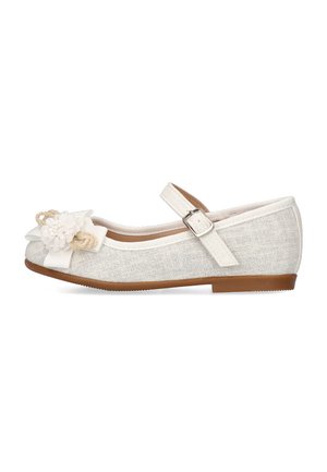 Zapato de tela color beige claro con una superficie texturada, que presenta una flor blanca decorativa y una correa con hebilla. Suela plana con un leve tacón.
