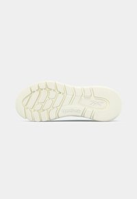 Podeszwa sneakersów Reebok w kremowym kolorze z teksturowanym wzorem gumowego gripu, z ukośnymi rowkami i logo wytłoczonym na środku.