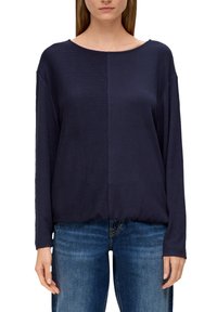 Dunkelblaues Langarmoberteil mit leicht rundem Ausschnitt, geripptem Struktur auf einer Seite und glatter Fläche auf der anderen Seite, kombiniert mit blauen Jeans.