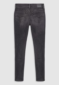 Tmavě šedé džíny z denimu s úzkým střihem, které mají dvě zadní kapsy a štítek na pase. Hladká textura s minimálním vyblednutím.