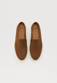 Pantofi slip-on maro cu partea superioară din piele perforată, talpă bej deschis și detalii cusute. Logo-ul brandului vizibil pe interior.