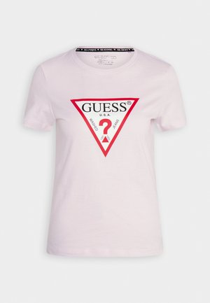 Biała koszulka z krótkim rękawem z czerwonym trójkątnym logo z napisem „GUESS U.S.A.” i „Washed Jeans” z czerwonym znakiem zapytania wewnątrz trójkąta.