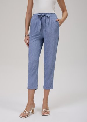 Light blue trousers with a textured fabric, cropped length, tied waistband, and side pockets. Complete with rolled cuffs for detail.