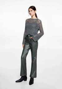 Harmaat neulottu villapaita, jossa on avoin kudonta ja liehuvat hihat, yhdistetty tummiin metallinhohtoisiin liehuviin housuihin ja nilkkureihin.