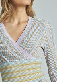 Gestreiftes Strickoberteil mit V-Ausschnitt, pastellfarbenen Akzenten in Gold und einem enganliegenden Taillenbund. Es hat eine strukturierte Rippung und lange Ärmel.