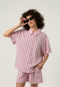 Rosa kortermet skjorte med vertikale marineblå striper, knappenedfront og krage, kombinert med matchende rosa shorts med lommer.