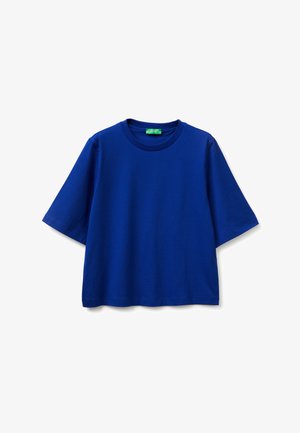 Niebieska, krótkorękawowa, oversize'owa koszulka z okrągłym dekoltem i zieloną metką przy wewnętrznym kołnierzu, prezentowana na białym tle.