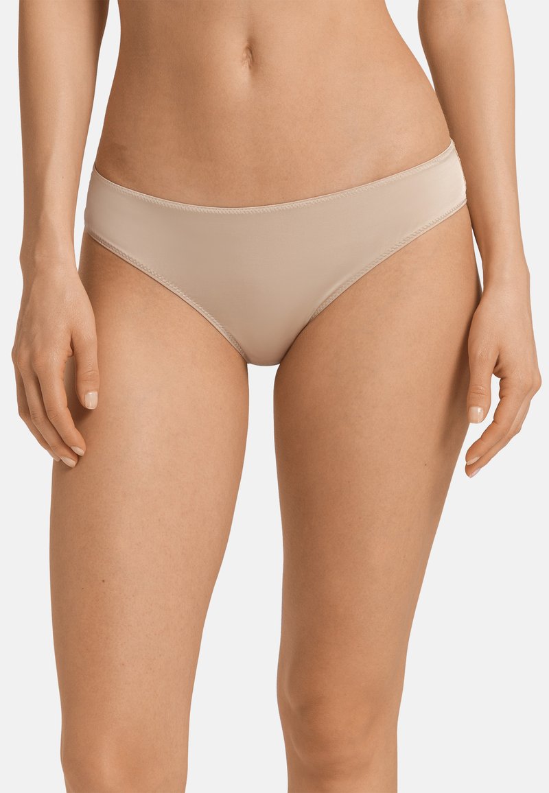 Slip bikini beige realizzati in tessuto liscio, con un design a vita bassa e dettagli di cucitura minimi per un aspetto senza soluzione di continuità.
