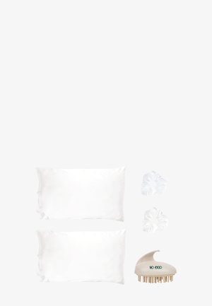 Zwei weiße Satin-Kissenbezüge, zwei weiße Haargummis und ein beige umweltfreundlicher Kopfhautmassager mit grünem Text an der Seite.