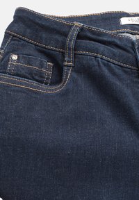 Mörkblå denimjeans med en slät textur, med kontrasterande orange sömmar, en liten framficka och en klassisk midjebandsdesign.