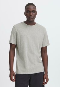 Camiseta de manga corta gris, hecha de un tejido suave, con un escote redondo y un sutil logo en el pecho. Corte casual con un diseño liso.