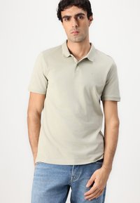 Lysegrønn polo skjorte laget av bomull, med klassisk krage, korte ermer, og en liten logo på brystet. Sammen med blå jeans.