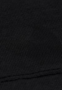 Černá pletená tkanina s hladkým povrchem, jemným žebrováním a subtilním leskem, s viditelným švem na spodní části.