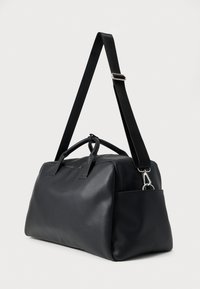 Čierna syntetická kožená cestovná taška s dvoma hornými rukoväťami a odnímateľným ramenným popruhom. Má bočné vrecko a elegantný, hladký povrch.