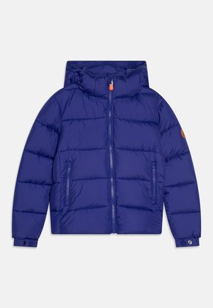 Giacca imbottita blu con cappuccio, zip frontale, due tasche laterali e una patch con logo sulla manica. Texture liscia e design caldo.