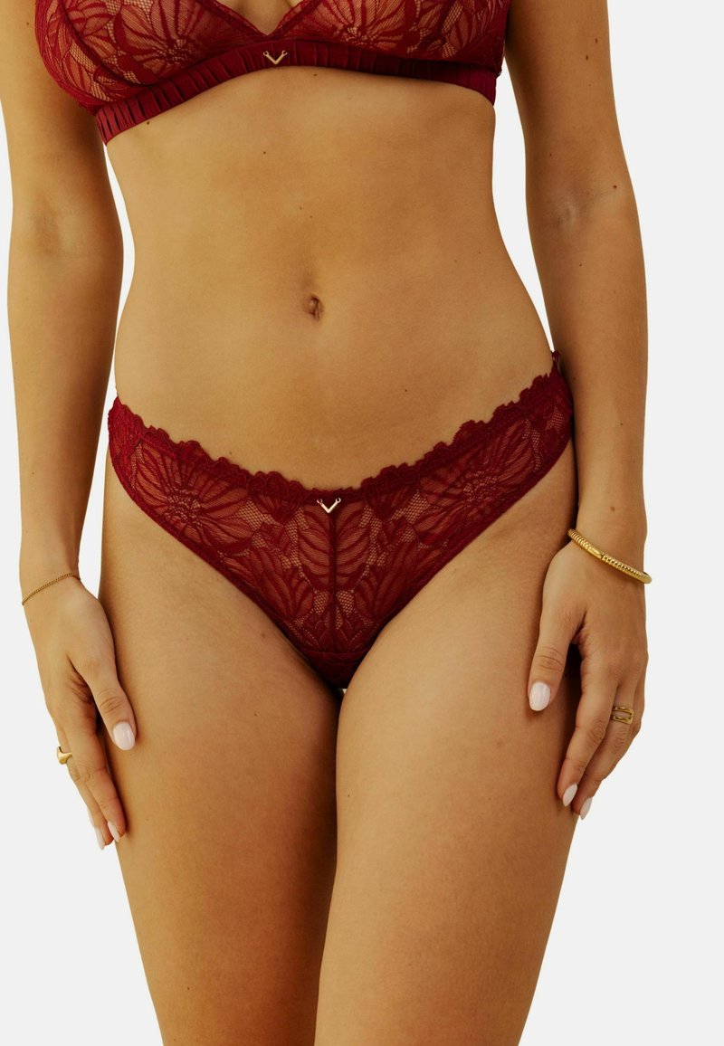 Ensemble en dentelle bordeaux avec soutien-gorge et culotte, orné de motifs floraux, de bords festonnés et de détails délicats. Texture douce et transparente mettant en valeur un design complexe.
