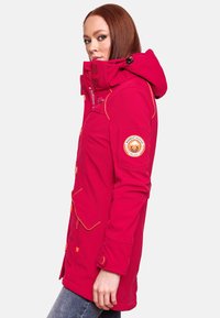 Bright pink, insulated parka with a hood, contrasting orange stitching, multiple pockets, and an emblem on the left sleeve.