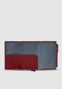 Portafoglio rosso e blu con esterno in pelle liscia, dotato di chiusura a zip e scomparto per carte. L'interno presenta una fodera blu dalla texture lavorata.