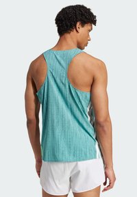 Helles türkisfarbenes Tanktop mit strukturiertem Muster, Racerback-Design und weißen Seitenakzenten. Kombiniert mit weißen Sportshorts.