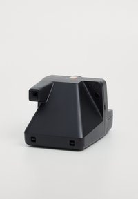 Compact black camera with a geometric design, featuring a textured surface, a lens protrusion, and a small button detail on the side.