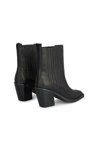 Botas de tobillo de cuero negro con punta cuadrada, paneles laterales acanalados y un tacón grueso. Presentan una textura suave y un diseño minimalista.
