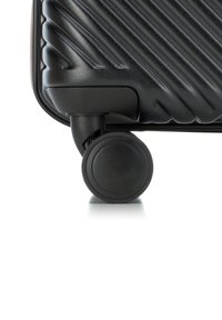 Valigia nera con una superficie testurizzata caratterizzata da scanalature diagonali. Include una robusta ruota nera rotonda per la mobilità alla base.